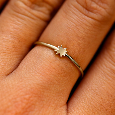 Close up view of a models fingers wearing a champagne gold 8 pointed star ring