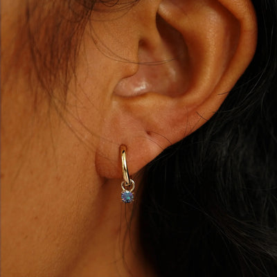 Close up view of a model's ear wearing a champagne gold Alexandrite Charm on a Curvy Huggie Hoop