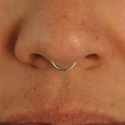Close up view of a model's nose wearing a 14k champagne gold Small Seamless Huggie Hoop in a septum piercing