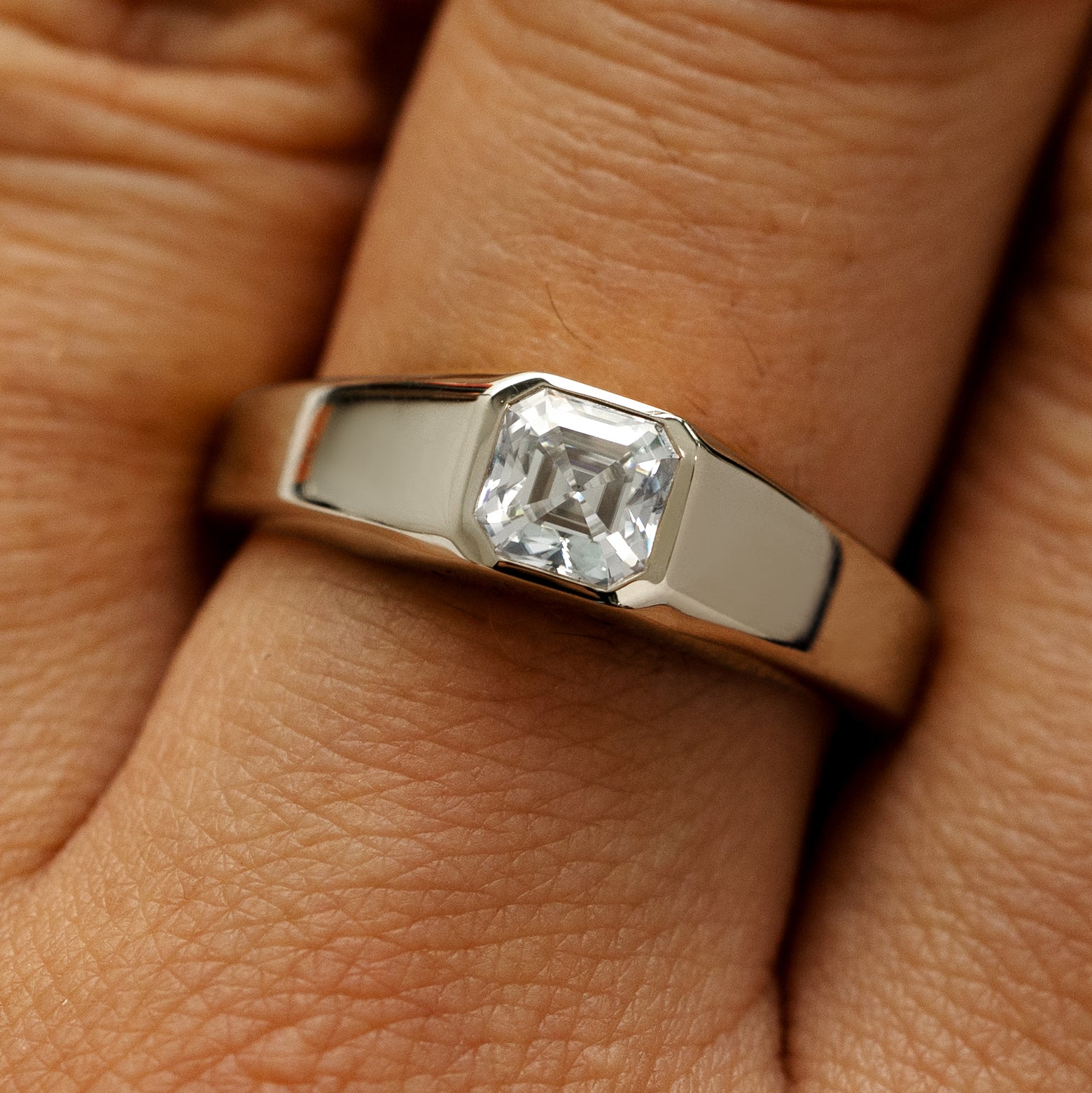 Close up view of a models hand wearing a 14k champagne gold asscher lab gemstone ring