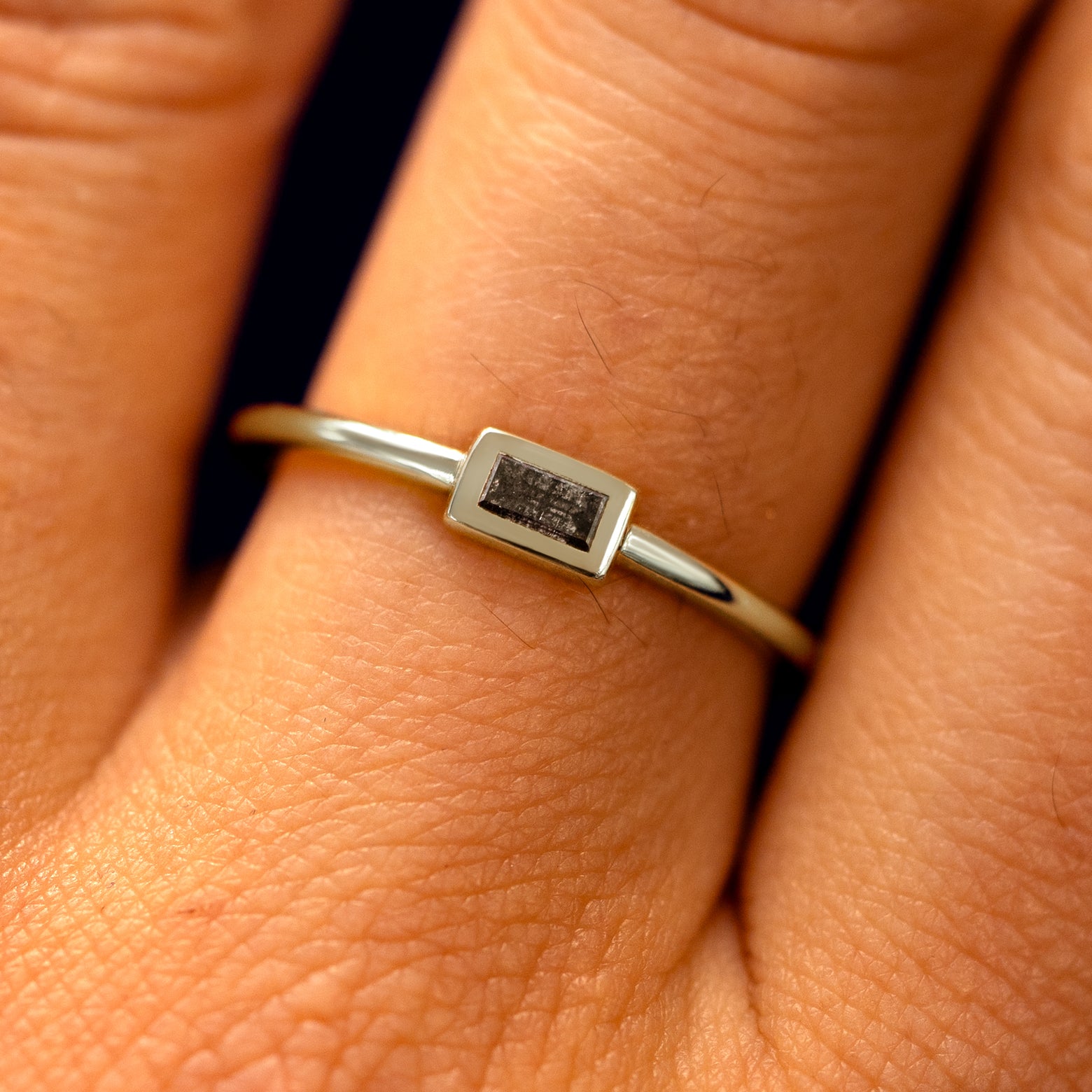 Close up view of a model's fingers wearing a 14k champagne gold Baguette Salt and Pepper Diamond Ring
