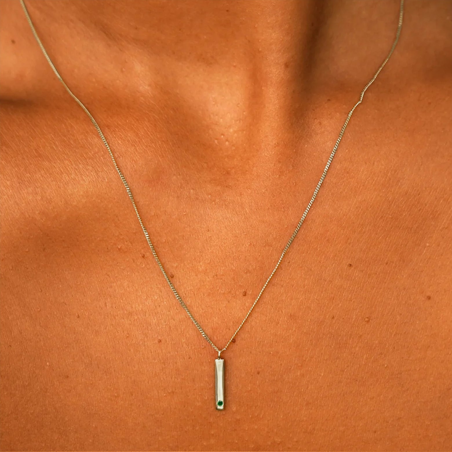 Close up view of a model's neck wearing a solid champagne gold emerald Gemstone Bar Necklace