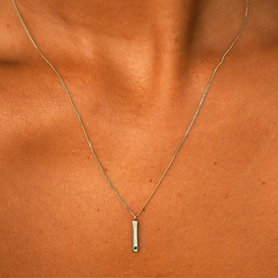 Close up view of a model's neck wearing a solid champagne gold emerald Gemstone Bar Necklace