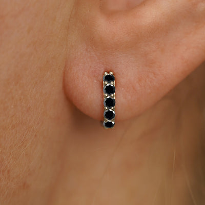 Close up view of a model's ear wearing a champagne gold mini Black Diamond Huggie Hoop
