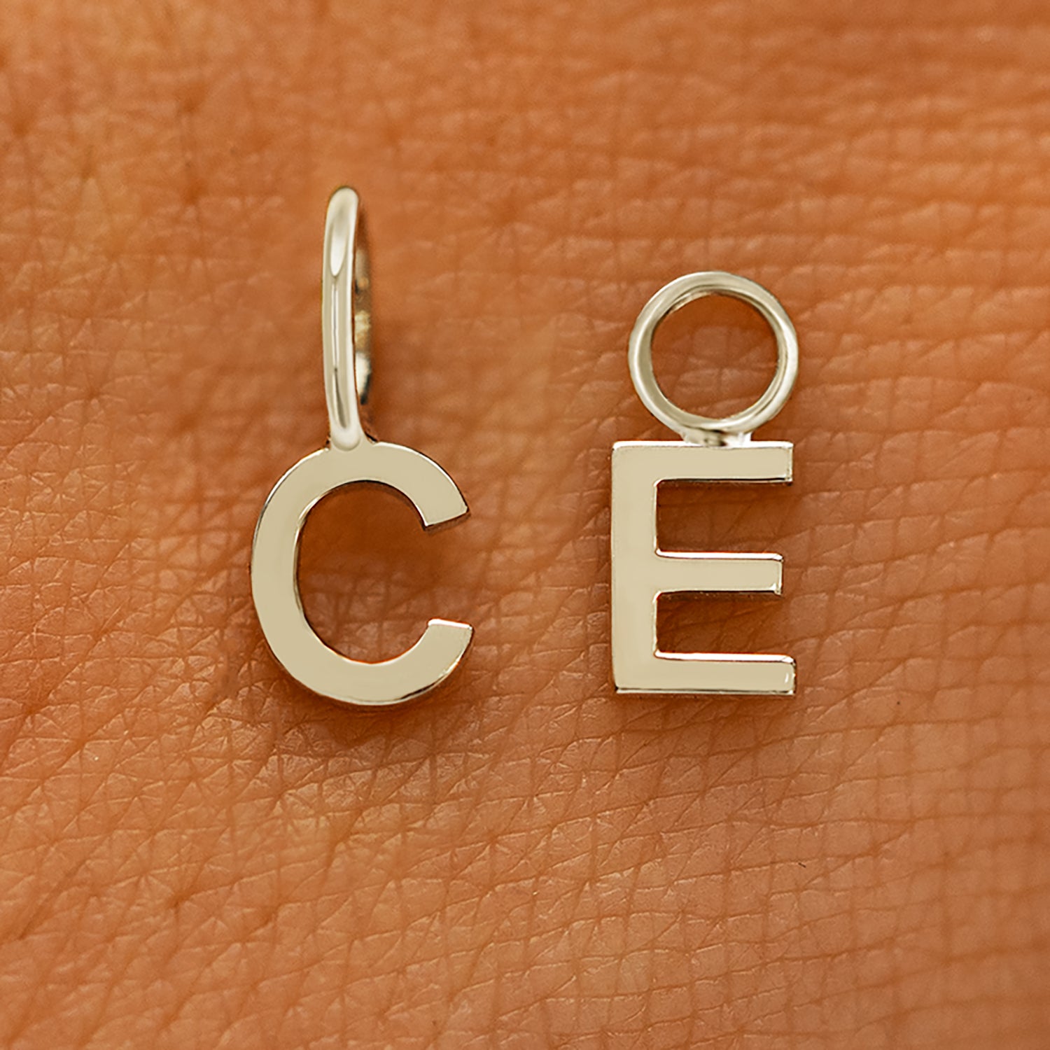 Two versions of the Block Initial Charm in the letters C and E showing For Chain and For Earring options in champagne gold