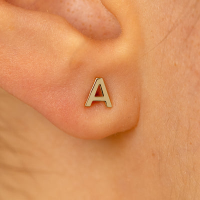 Close up view of a models ear wearing a 14k champagne gold letter A block initial stud earring