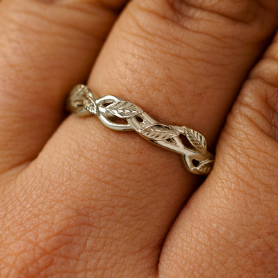 A solid 14k champagne gold braided leaves and vines ring on a model's finger
