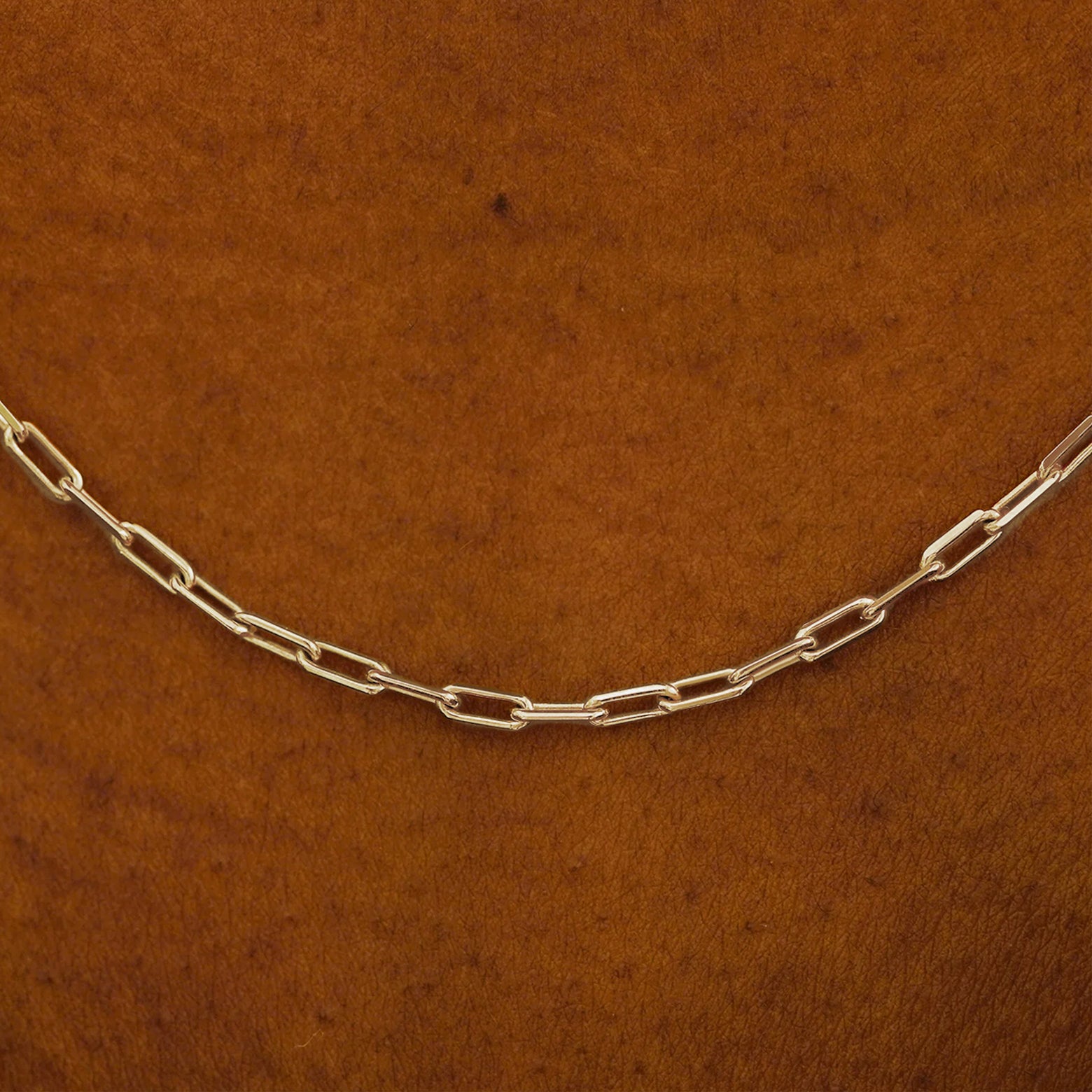 Close up view of a model in a white shirt wearing a solid champagne gold Butch Chain