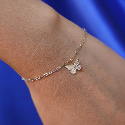 Close up view of a model's wrist wearing a champagne gold Butterfly Charm on a Butch Chain Bracelet