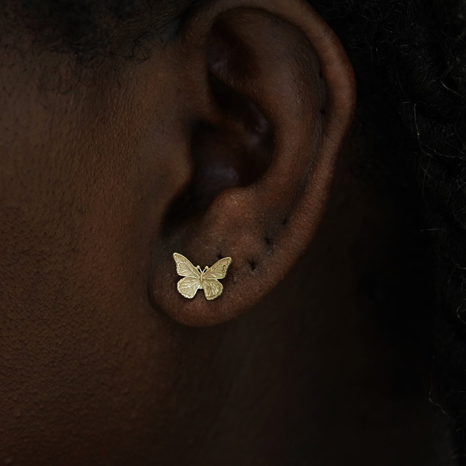 Close up view of a model's ear wearing a 14k champagne gold Butterfly Earring