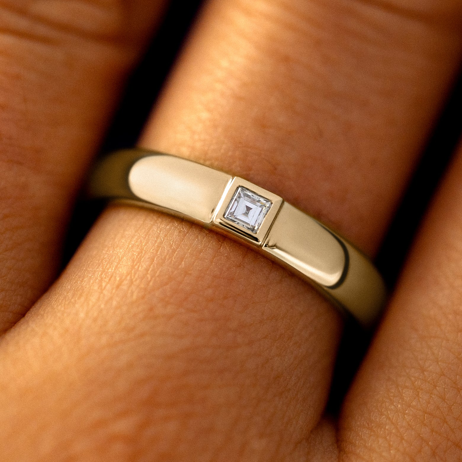 Close up view of a model's fingers wearing a 14k champagne gold Square Carre Cut Diamond Band