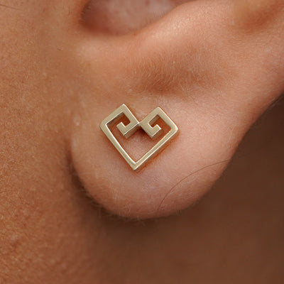 Close up view of a model's ear wearing a champagne gold Chere Heart Earring
