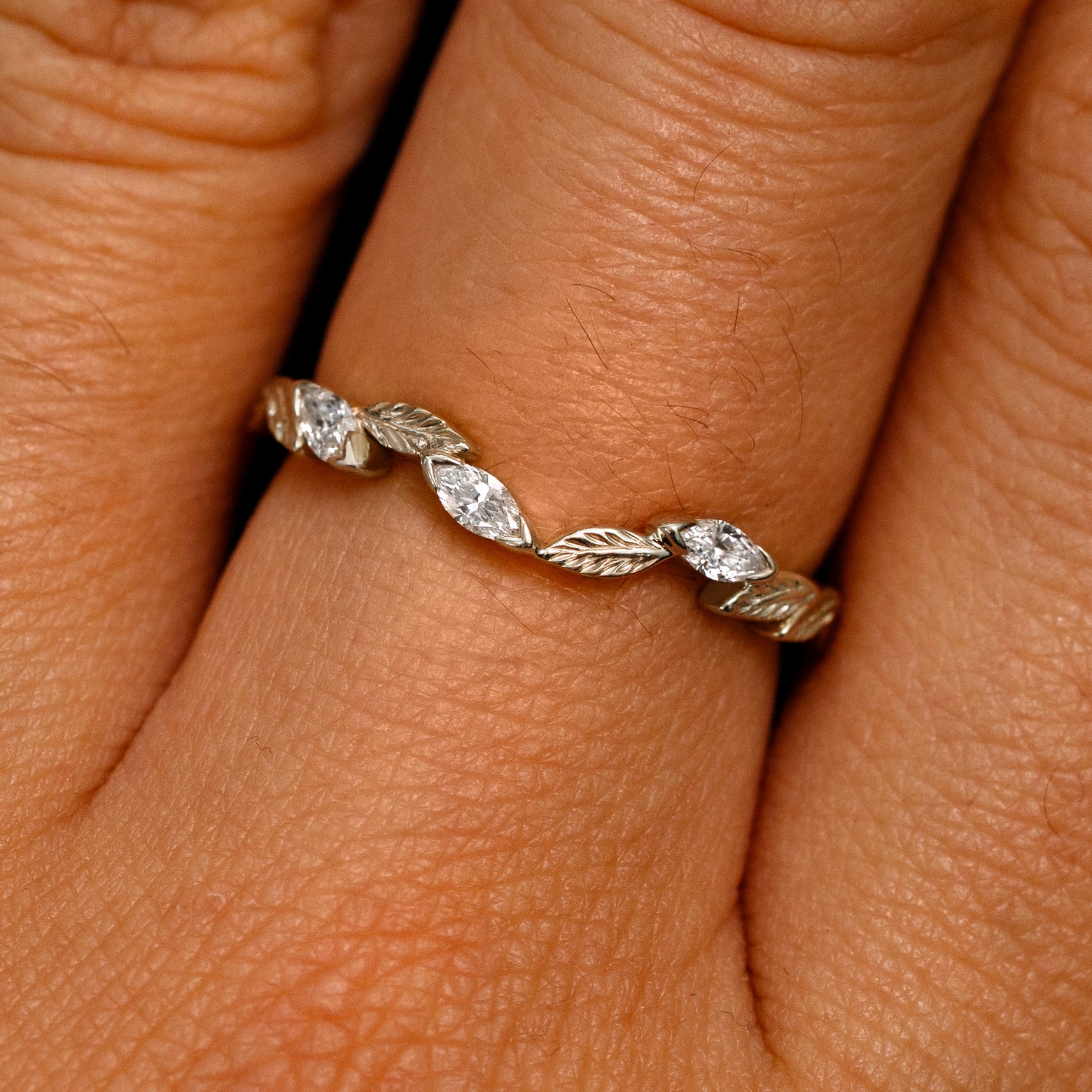 Close up view of a model's fingers wearing a 14k champagne gold Chevron Leaves and Marquise Diamonds Band