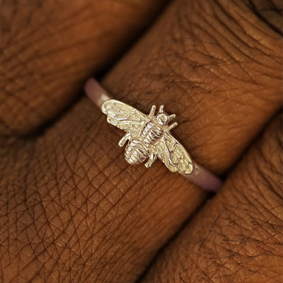 Close up view of a model's hand wearing a 14k solid champagne gold Curvy Bee Ring