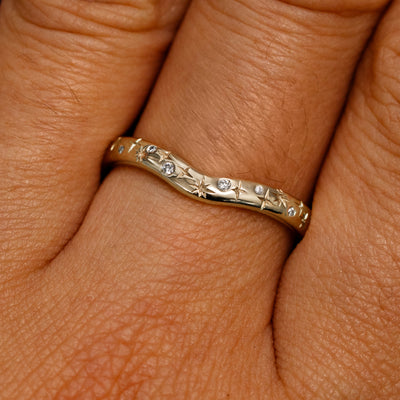 Close up view of a model's fingers wearing a 14k champagne gold Curvy Chevron Diamond Stars Band