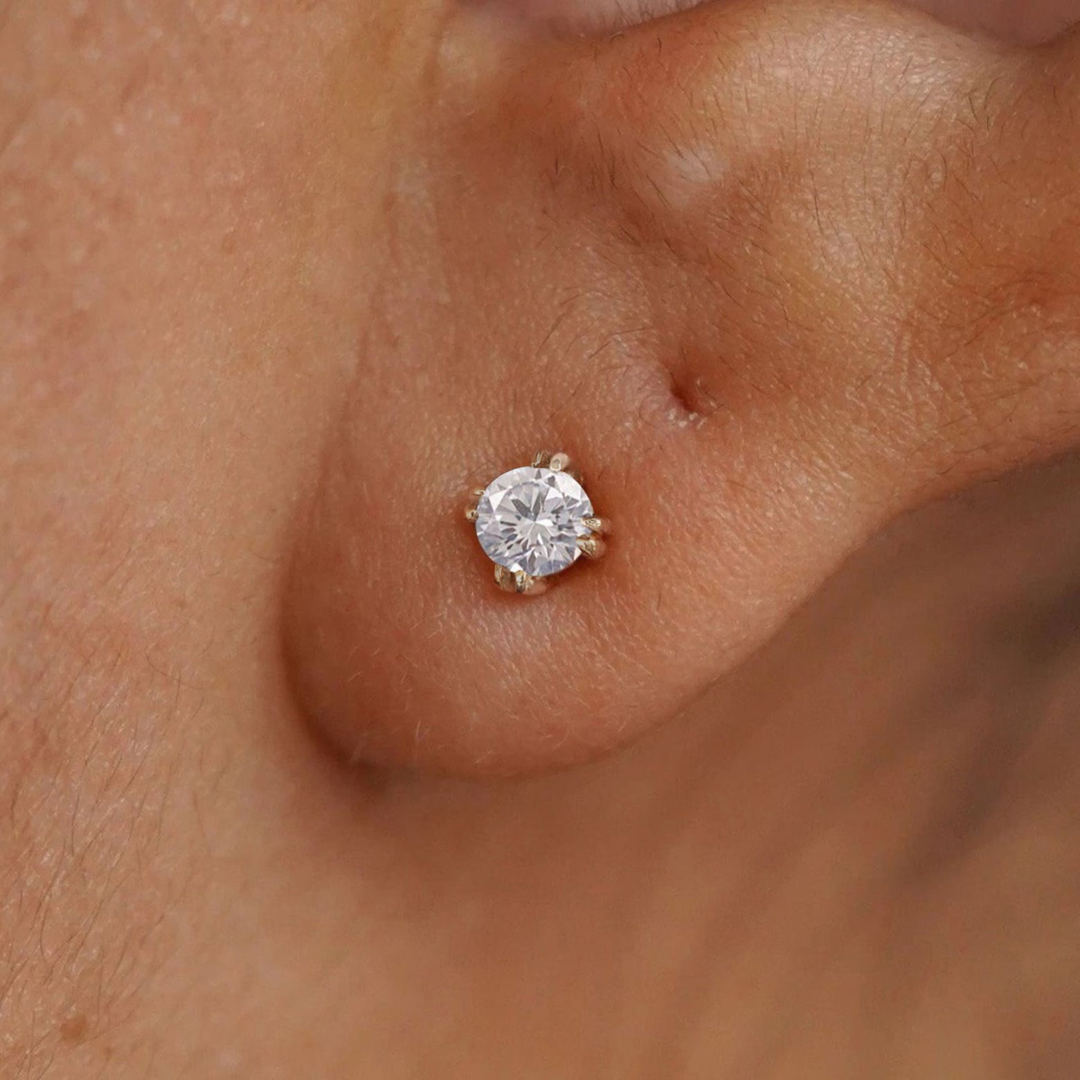 Close up view of a model's ear wearing a 14k rose gold Diamond Earring