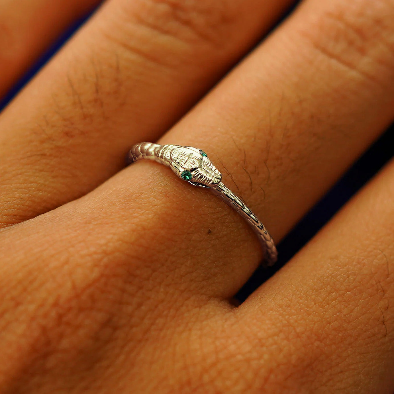 Close up view of a model's hand wearing a champagne gold emerald Gemstone Ouroboros Snake Ring