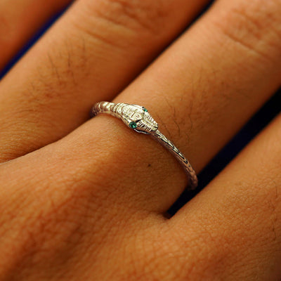 Close up view of a model's hand wearing a champagne gold emerald Gemstone Ouroboros Snake Ring
