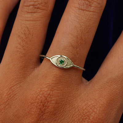 Close up view of a model's hand wearing a champagne gold Evil Eye Ring in the Emerald gemstone option