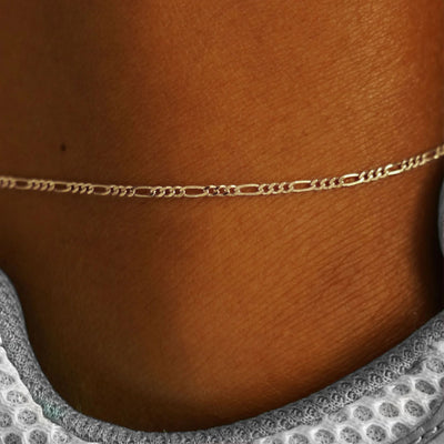 Close up view of a model's ankle wearing a champagne gold Figaro Anklet