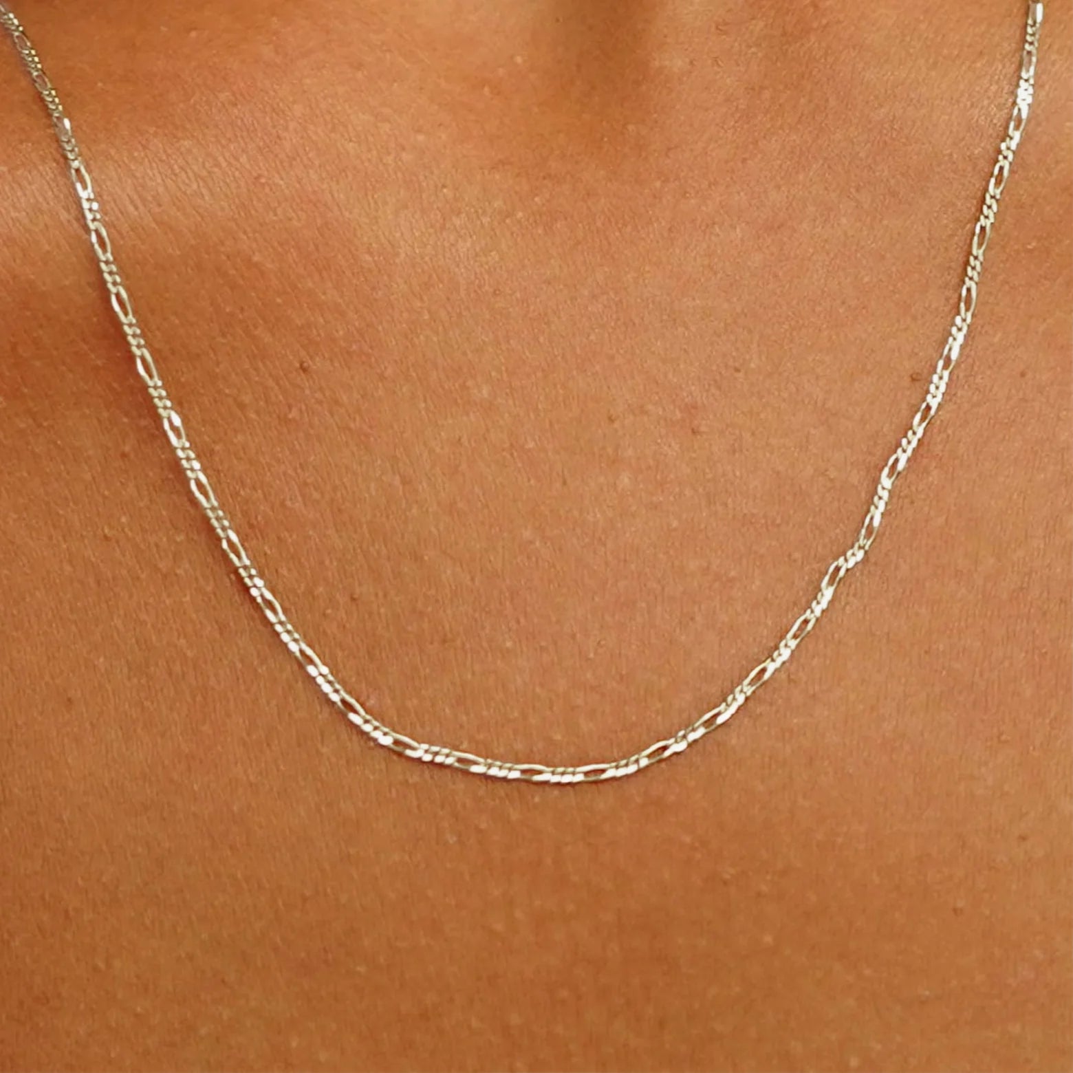 Close up view of a model's neck wearing a solid champagne gold Figaro Chain