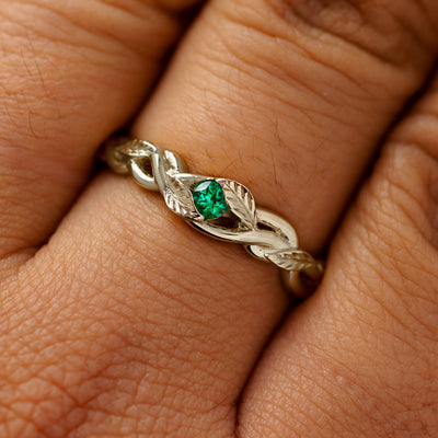 A solid 14k champagne gold emerald leaves and vines ring on a model's finger