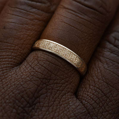 Close up view of a model wearing a solid 14k champagne gold diamond patterned band