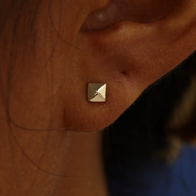 Close up view of a model's ear wearing a champagne gold Pyramid Earring