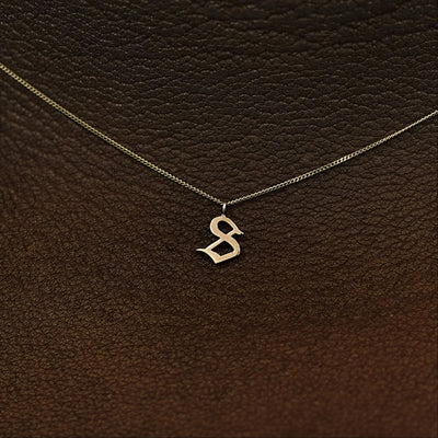 Close up view of a model's neck wearing a 14k solid champagne gold Initial Charm Necklace in the letter S