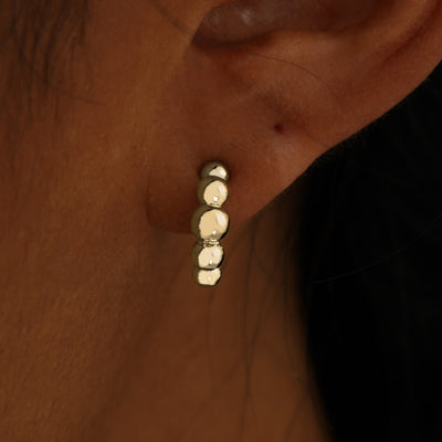 Close up view of a model's ear wearing a 14k champagne gold Mini Puffy Beaded Hoop