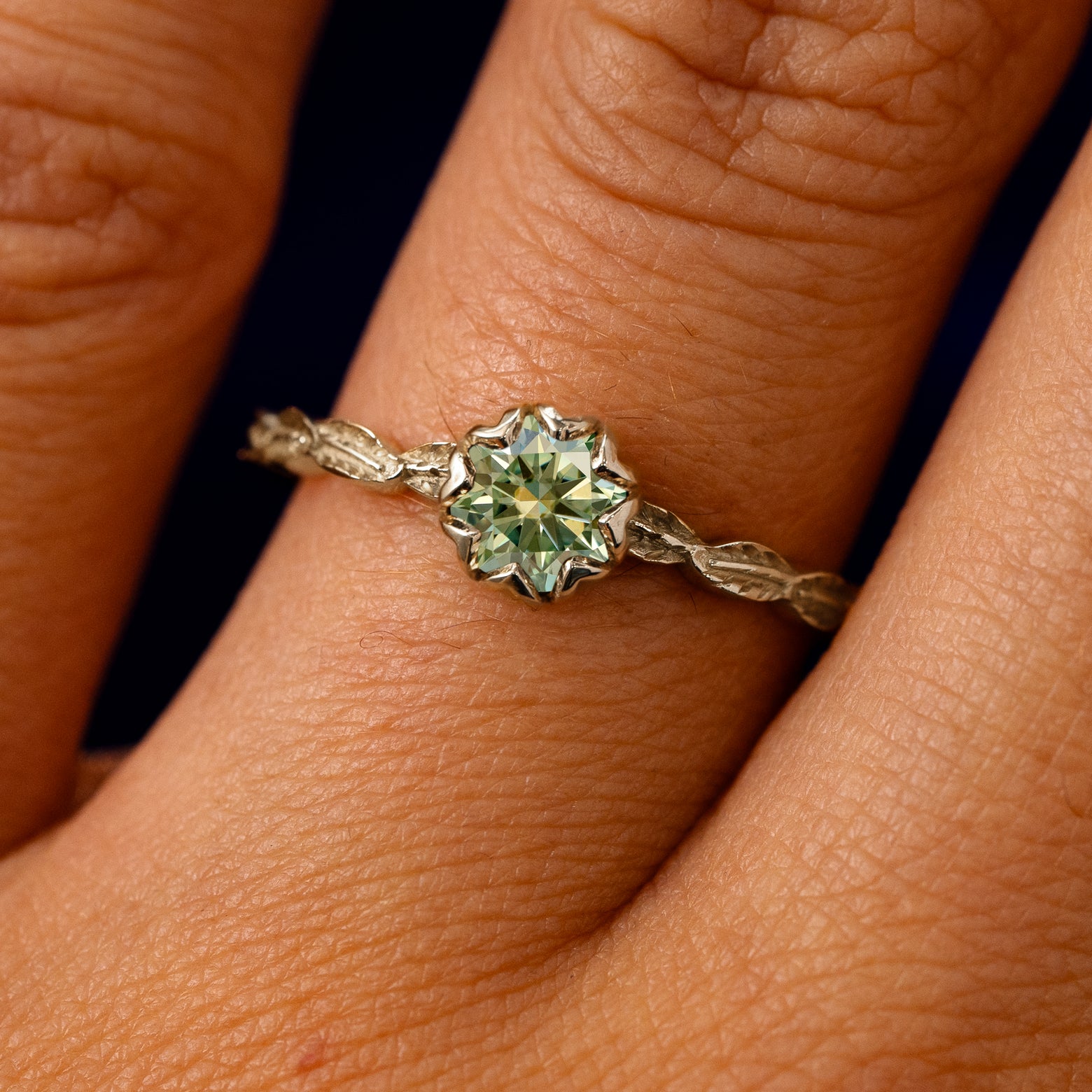 A solid 14k champagne gold Green Moissanite Leaf Ring on a model's finger