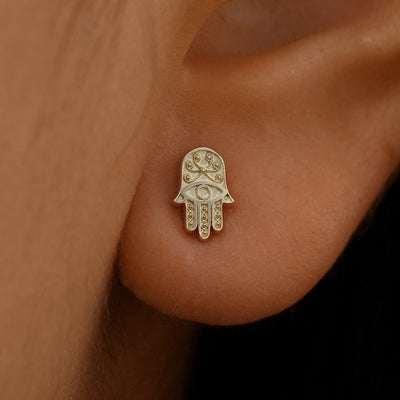 Close up view of a model's ear wearing a 14k champagne gold Hamsa Earring