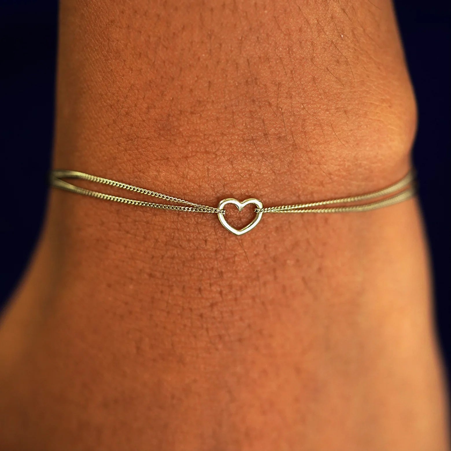A model's wrist wearing a solid chamapagne gold Heart Bracelet