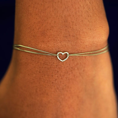 A model's wrist wearing a solid chamapagne gold Heart Bracelet