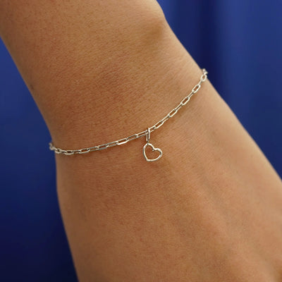 Close up view of a model's wrist wearing a champagne gold Heart Charm on a Butch Bracelet