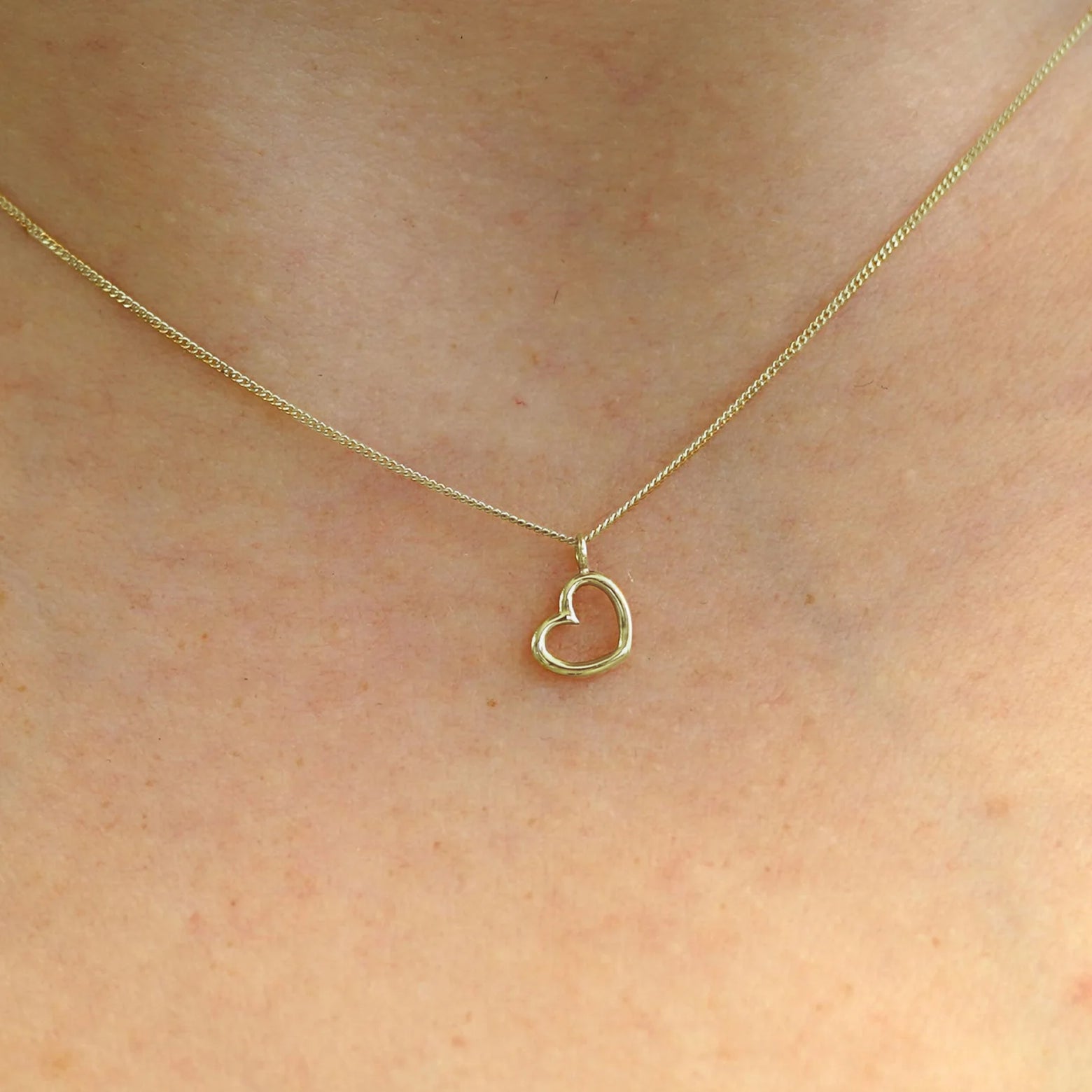 Close up view of a model's neck wearing a 14k champagne gold Heart Necklace