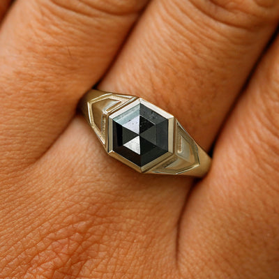 Close up view of a model's fingers wearing a 14k champagne gold hexagon black diamond engraved transformation ring