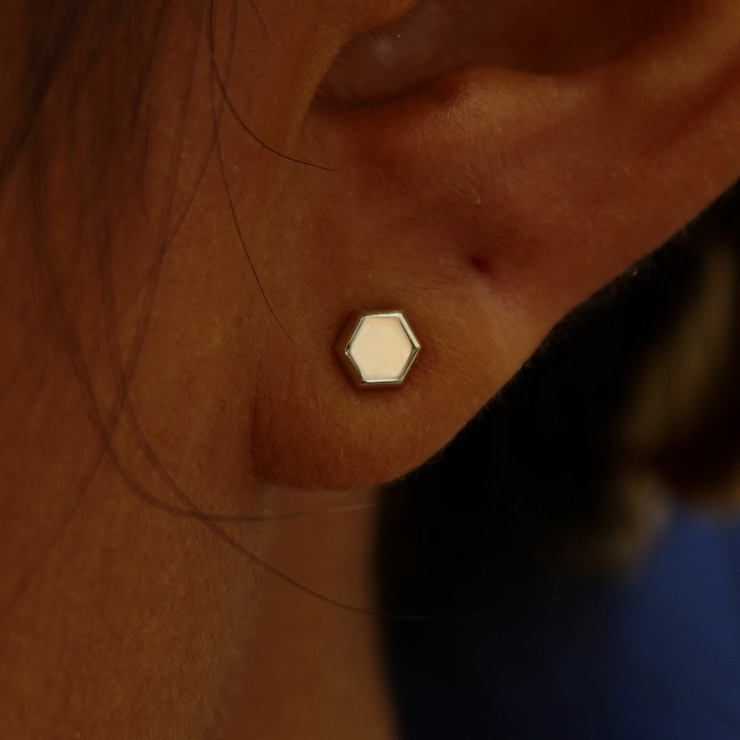 Close up view of a model's ear wearing a champagne gold Hexagon Earring