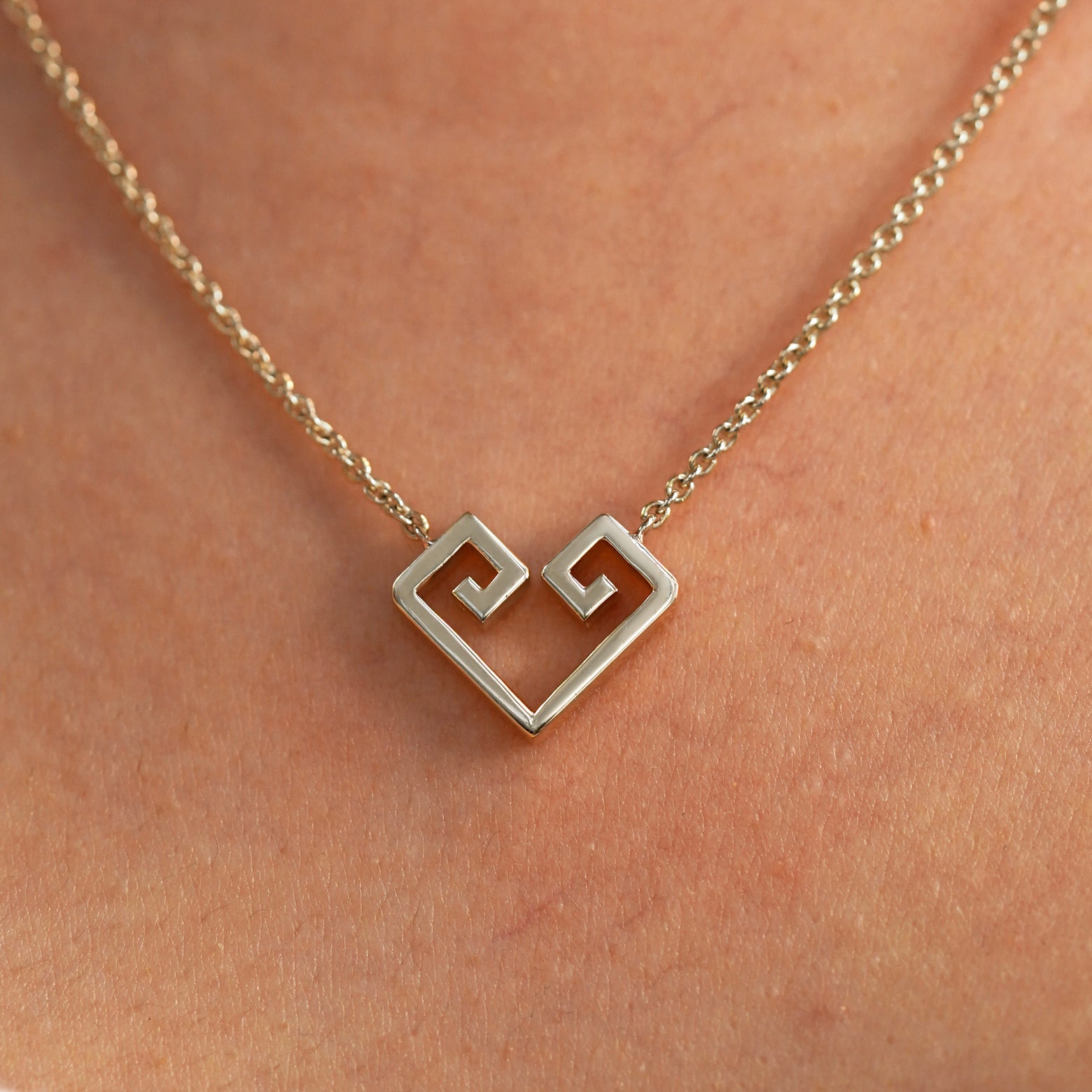 A close up view of a model's neck wearing a champagne gold Large Chere Heart Necklace