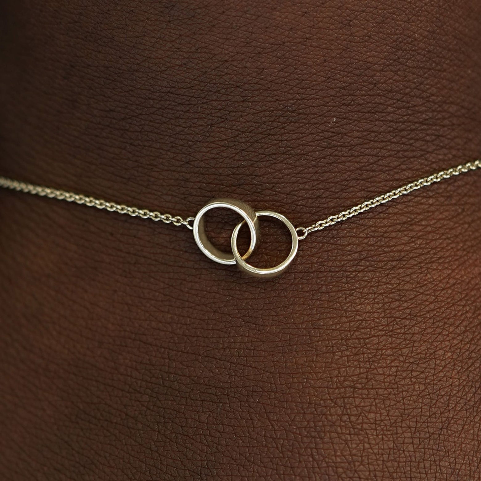 Close up view of a model's wrist wearing a champagne solid gold Bound Together Bracelet