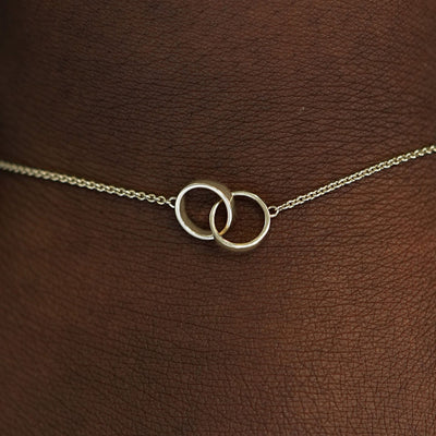 Close up view of a model's wrist wearing a champagne solid gold Bound Together Bracelet