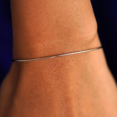 Close up view of a model's wrist wearing a champagne gold Line Bangle Bracelet