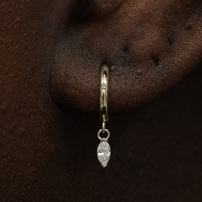 Close up view of a model's ear wearing a champagne gold Marquise Lab Diamond Dangle Huggie Hoop