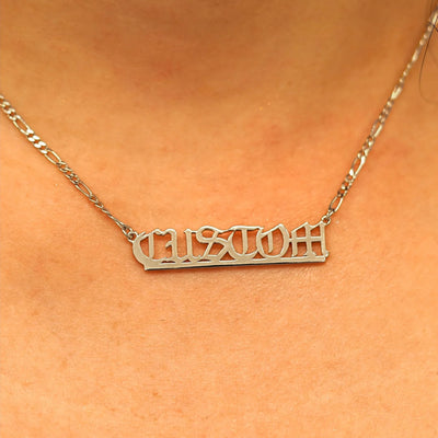 Close up view of a model's neck wearing a Medium Custom Nameplate necklace that reads the word Custom