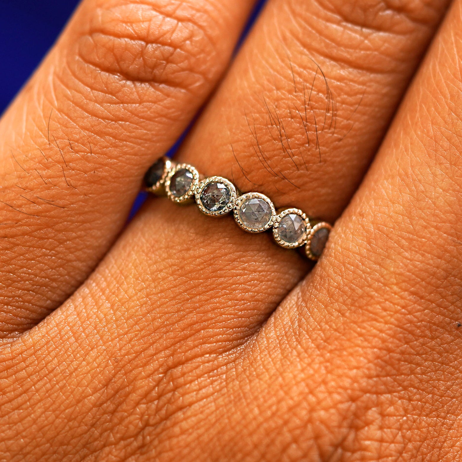 Close up view of a model's hand wearing a 14k champagne gold Milgrain Diamond Band