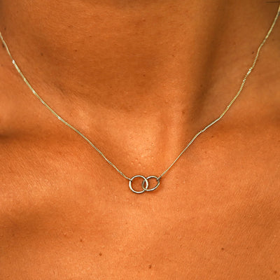 Close up view of a model's neck wearing a solid champagne gold Mini Bound Together Necklace