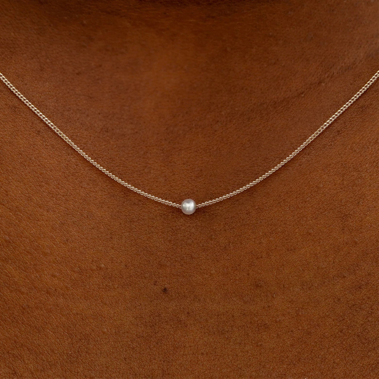 Close up view of a model's neck wearing a champagne gold Pearl Slide Necklace with a 2mm pearl