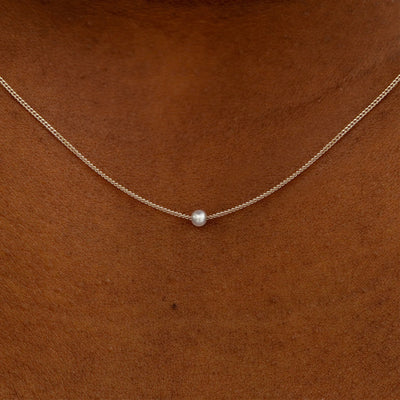 Close up view of a model's neck wearing a champagne gold Pearl Slide Necklace with a 2mm pearl