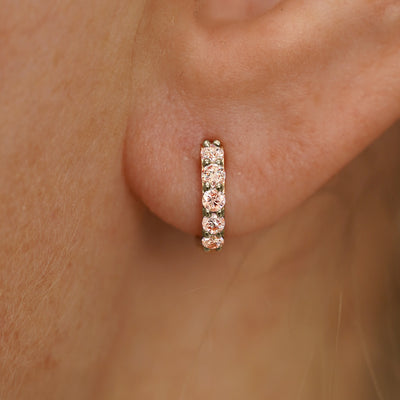 Close up view of a model's ear wearing a champagne gold Small Pink Lab Diamond Huggie Hoop