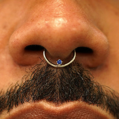 Close up view of a model's nose wearing a 14k champagne gold sapphire Raised Gemstone Septum